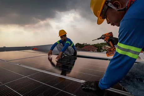 Instalare de panouri solare de către muncitori pe un acoperiș.