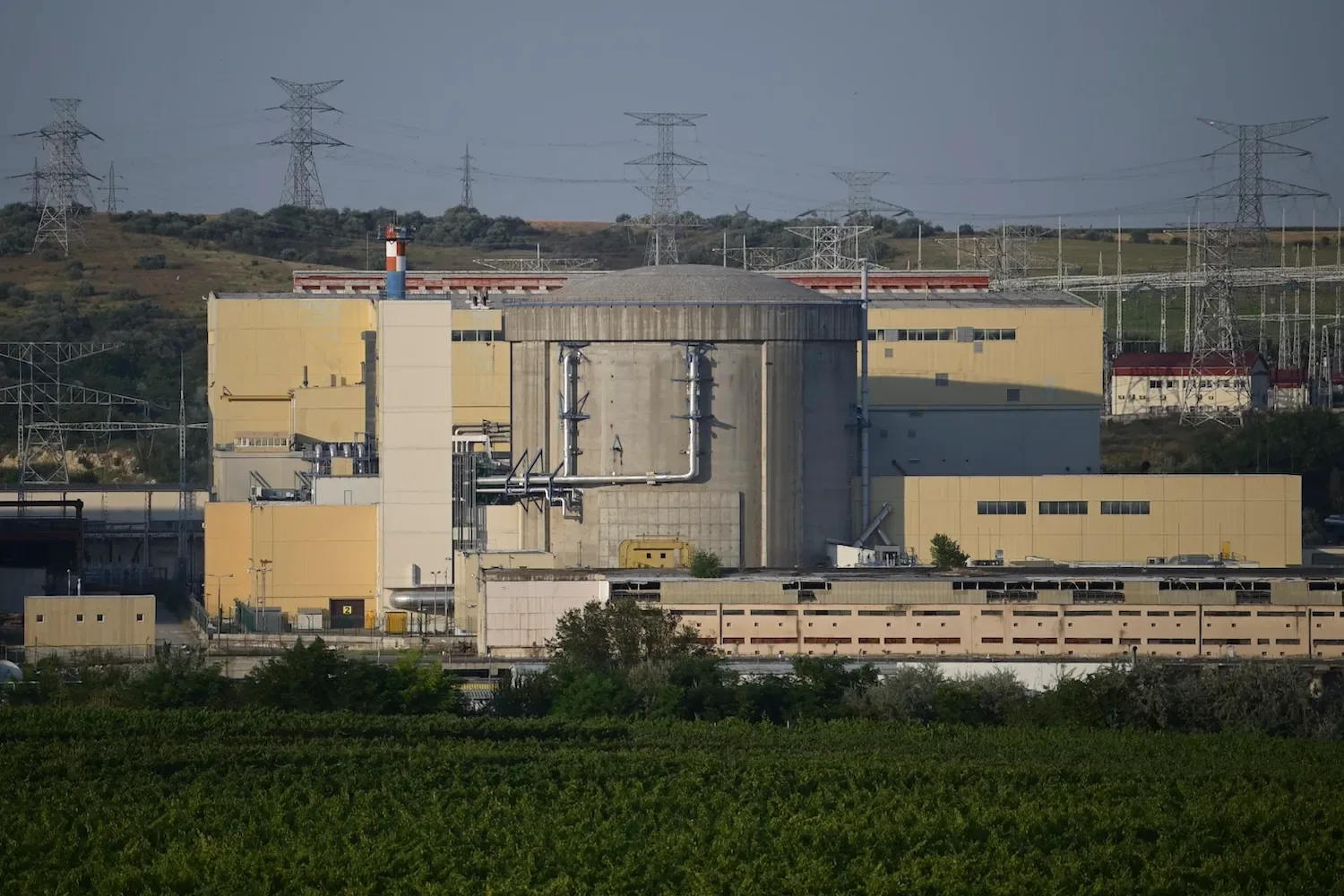 Centrala nucleară de la Cernavodă, înconjurată de peisaj verde, cu turnuri de răcire vizibile.