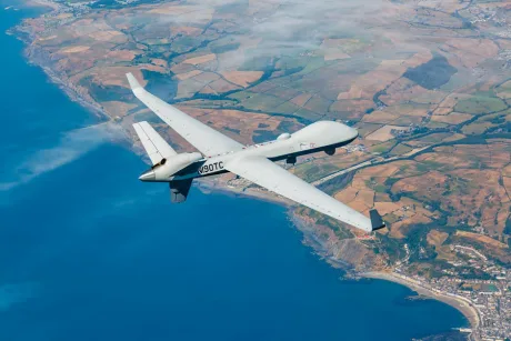 Dronă MQ-1 Predator zburând deasupra unei regiuni costiere.