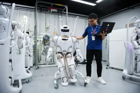Un robot interacționează cu un student într-un laborator tehnologic.
