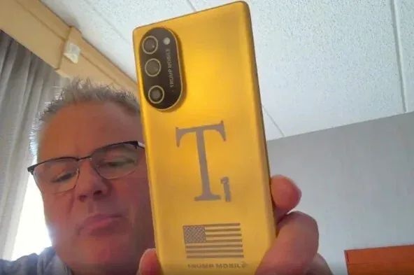 Un bărbat ține un telefon Trump T1 cu un design nou și logo-ul steagului SUA.
