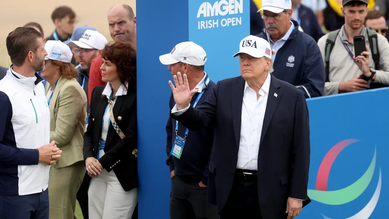 Donald Trump salutând la un eveniment sportiv în Irlanda, înconjurat de oameni.