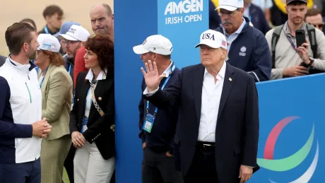 Donald Trump salutând la un eveniment sportiv în Irlanda, înconjurat de oameni.