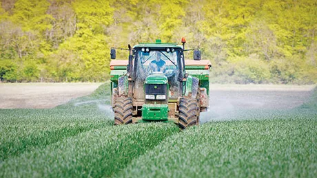 Tractor aplicând îngrășăminte pe câmpurile agricole din România.