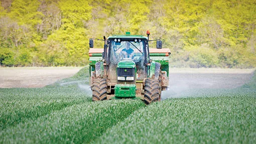 Tractor aplicând îngrășăminte pe câmpurile agricole din România.