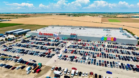 Magazinul La Cocoş din Oradea, plin de clienți și mașini parcate.