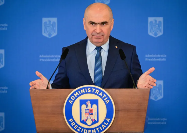 Ilie Bolojan la o conferință de presă, gesticulând.