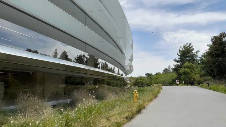 Clădire modernă Apple înconjurată de natură și vegetație.