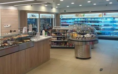 Interiorul unui magazin dintr-o benzinărie, cu produse expuse pe rafturi.