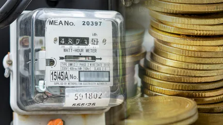 Contor de energie electrică lângă monede, simbolizând creșterea prețurilor.