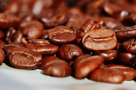 Boabe de cafea prăjite, simbolizând creșterea prețurilor pe piață.