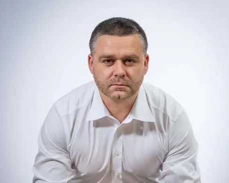 Ciprian Ciucu cu o expresie serioasă, îmbrăcat în cămașă albă.