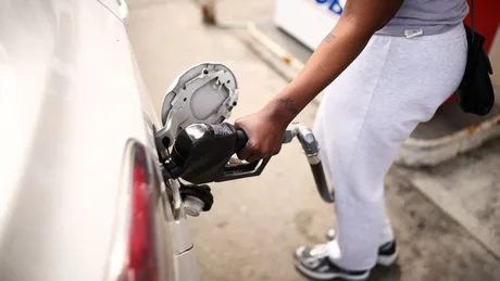 O persoană alimentează o mașină cu benzină la o stație de carburant.