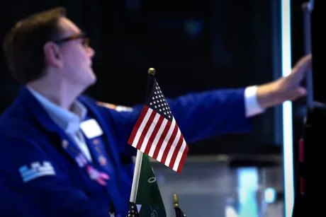 Un trader pe piața financiară, cu steagul american în fundal.