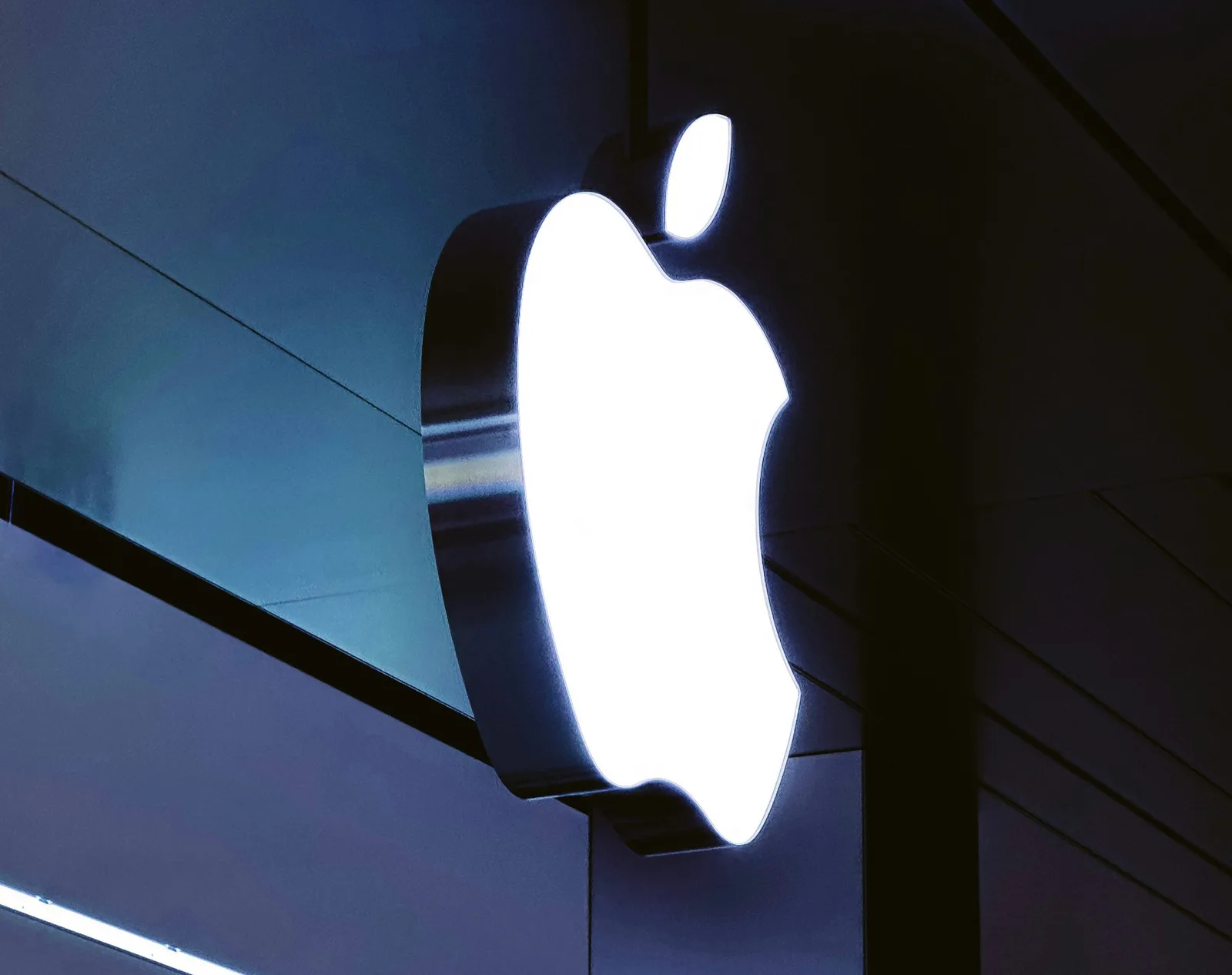 Logo-ul Apple iluminat pe un fundal întunecat.