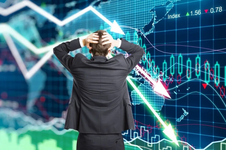 Un bărbat îngrijorat privind graficele economice în scădere.
