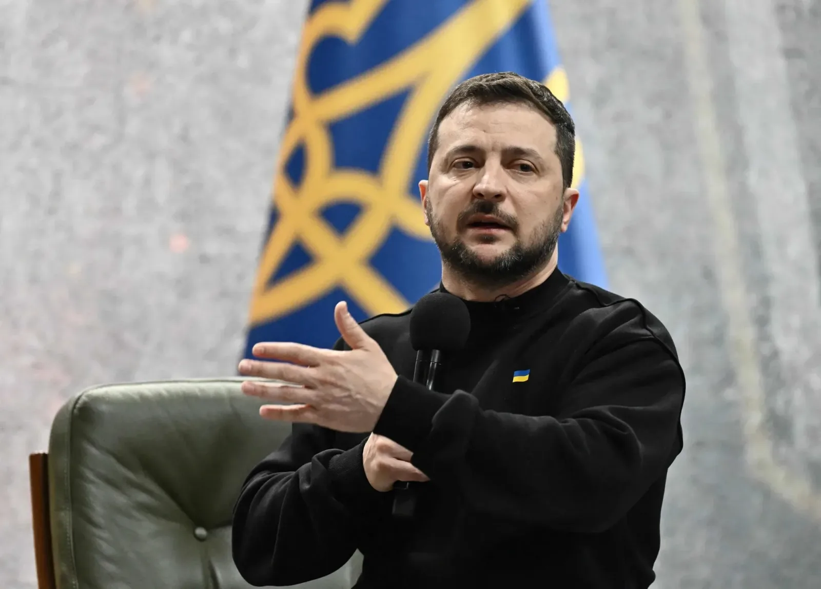 Zelenski vorbește la conferința de presă, cu steagul Ucrainei în fundal.