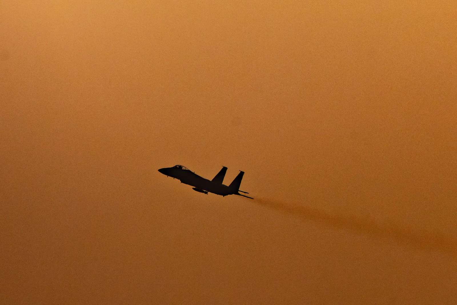 Avion de vânătoare israelian în zbor, pe fundal portocalie.