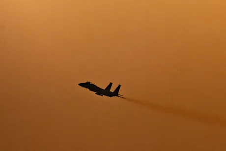 Avion de vânătoare israelian în zbor, pe fundal portocalie.