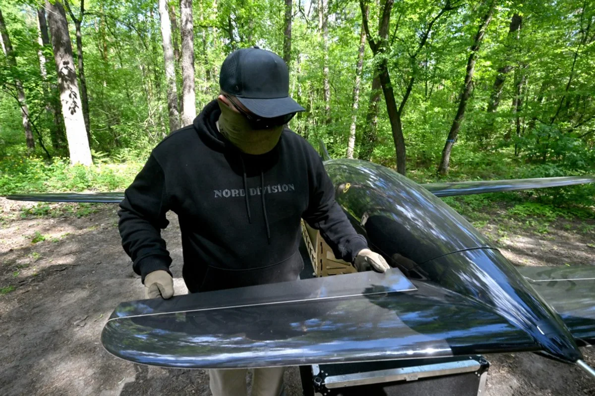 Un operator pregătește o dronă Begemot în pădure, pentru atacuri precise.