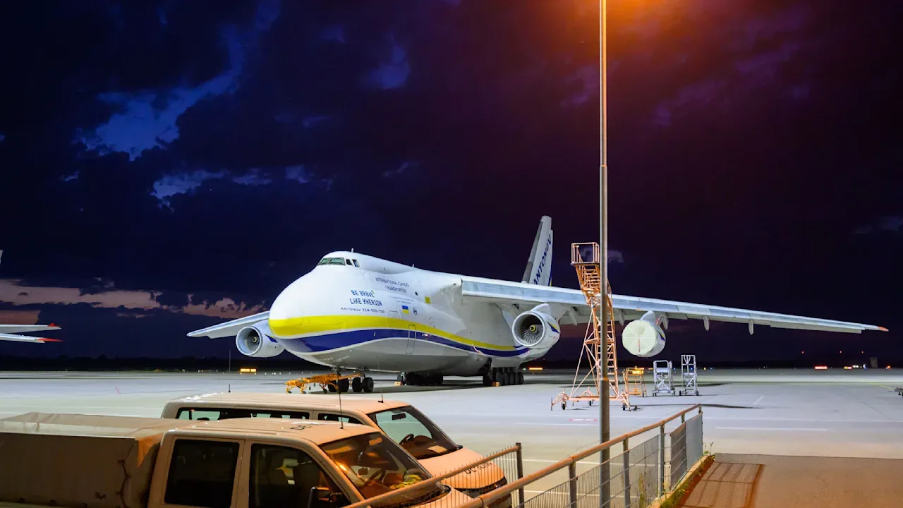 Avion pe aeroport, sub un cer întunecat, cu lumini de noapte.