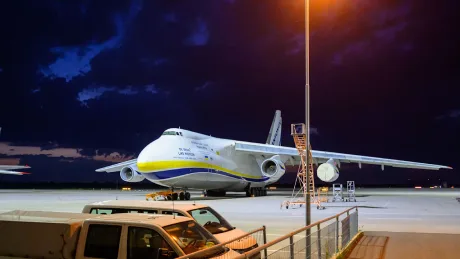Avion pe aeroport, sub un cer întunecat, cu lumini de noapte.