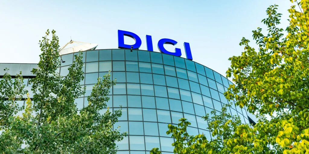 Sediul Digi Communications înconjurat de copaci verzi.