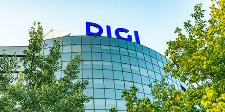 Sediul Digi Communications înconjurat de copaci verzi.