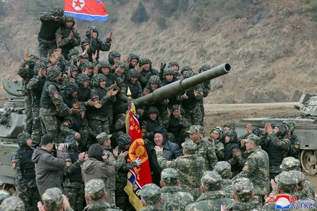 Militari nord-coreeni în timpul unei parade, cu steagul Coreei de Nord în fundal.