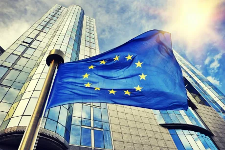 Steagul Uniunii Europene fluturând în fața unei clădiri moderne.