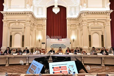 Nicușor Dan vorbește la o conferință de presă, cu steaguri în fundal.