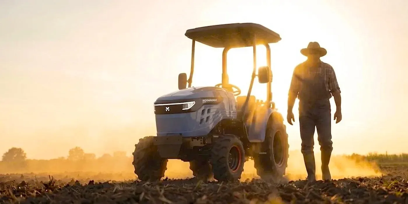 Tractor electric Moonrider 27 în acțiune pe câmp, cu soarele apunând în fundal.