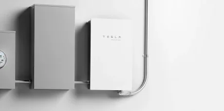 Invertoare solare Tesla instalate pe un perete, cu cabluri conectate.