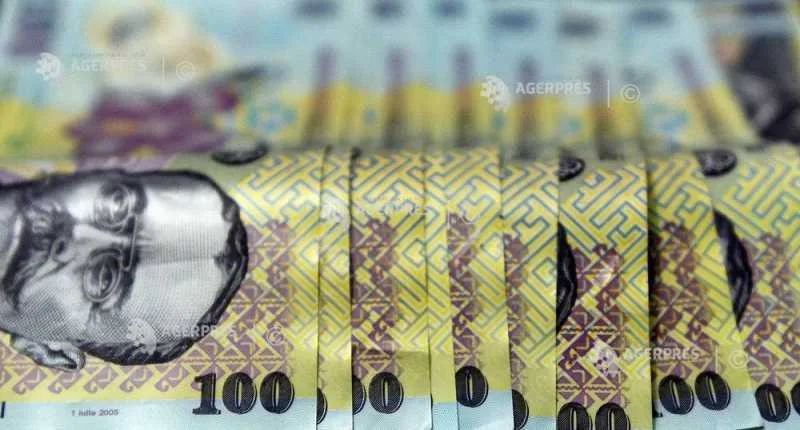 Bancnote românești de 100 lei aranjate pe masă.
