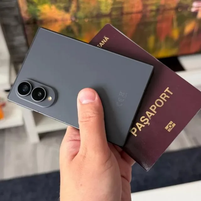 Un telefon pliabil în mână, alături de un pașaport, evidențiind noul format Galaxy Z Fold8.
