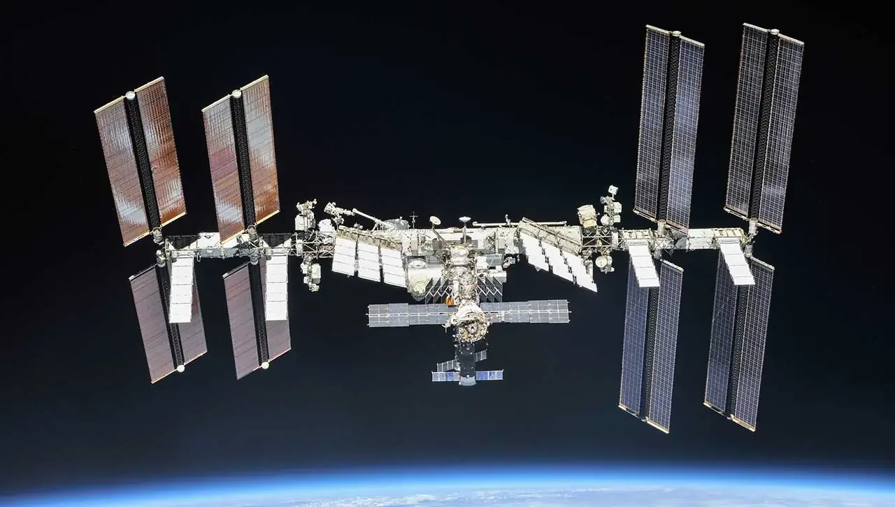 Stația Spațială Internațională văzută de la distanță, cu panouri solare extinse.