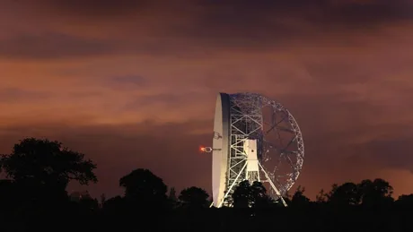 Un radiotelescop în noapte, captând semnale din univers.