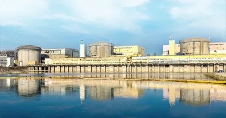 Centrala nucleară de la Cernavodă reflectată în apă, cu reactoare vizibile.