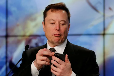 Elon Musk verificând telefonul în timpul unei prezentări.
