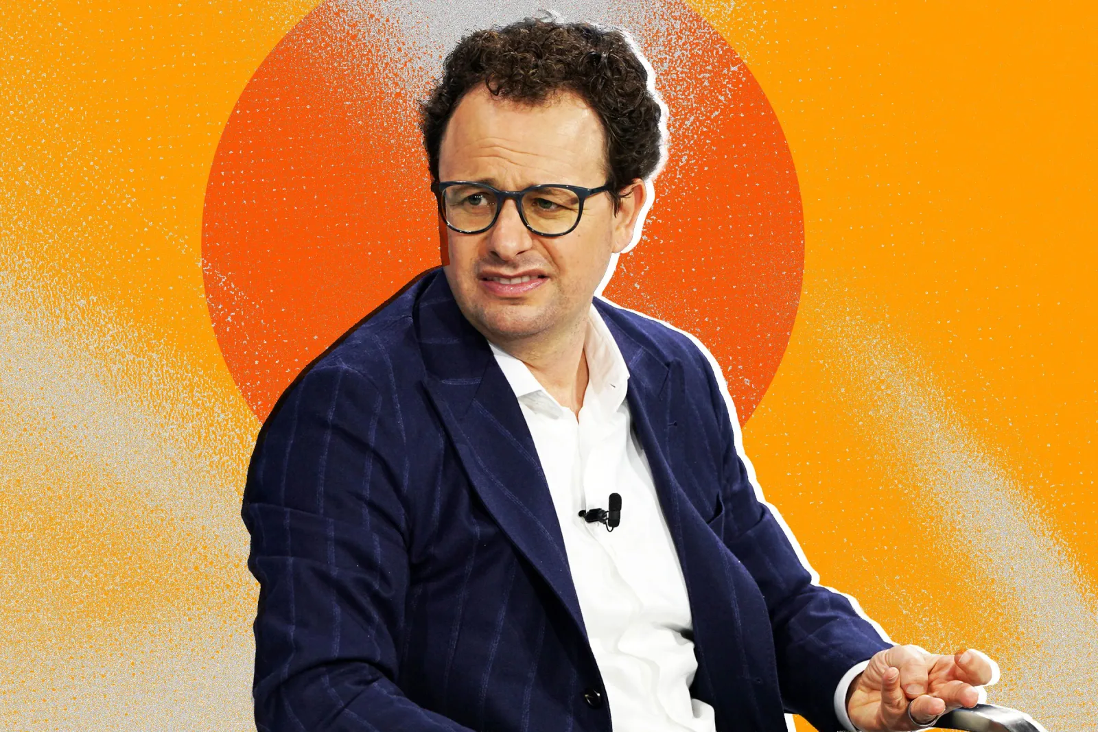 Un bărbat cu ochelari, îmbrăcat elegant, discutând despre tehnologia AI.