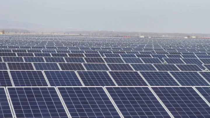 Panouri solare amplasate pe un teren vast, reflectând lumina soarelui.