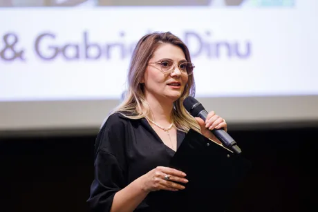 Prezentare a unei femei la un eveniment, vorbind la microfon.