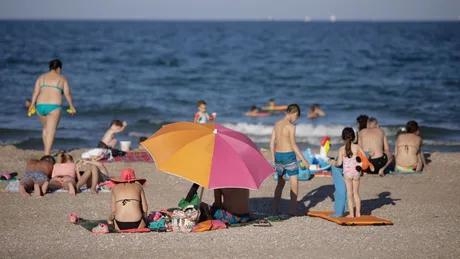 Oameni pe plaja Modern din Constanța, bucurându-se de soare și apă.