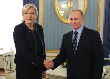 Marine Le Pen și Vladimir Putin se salută într-un cadru oficial.