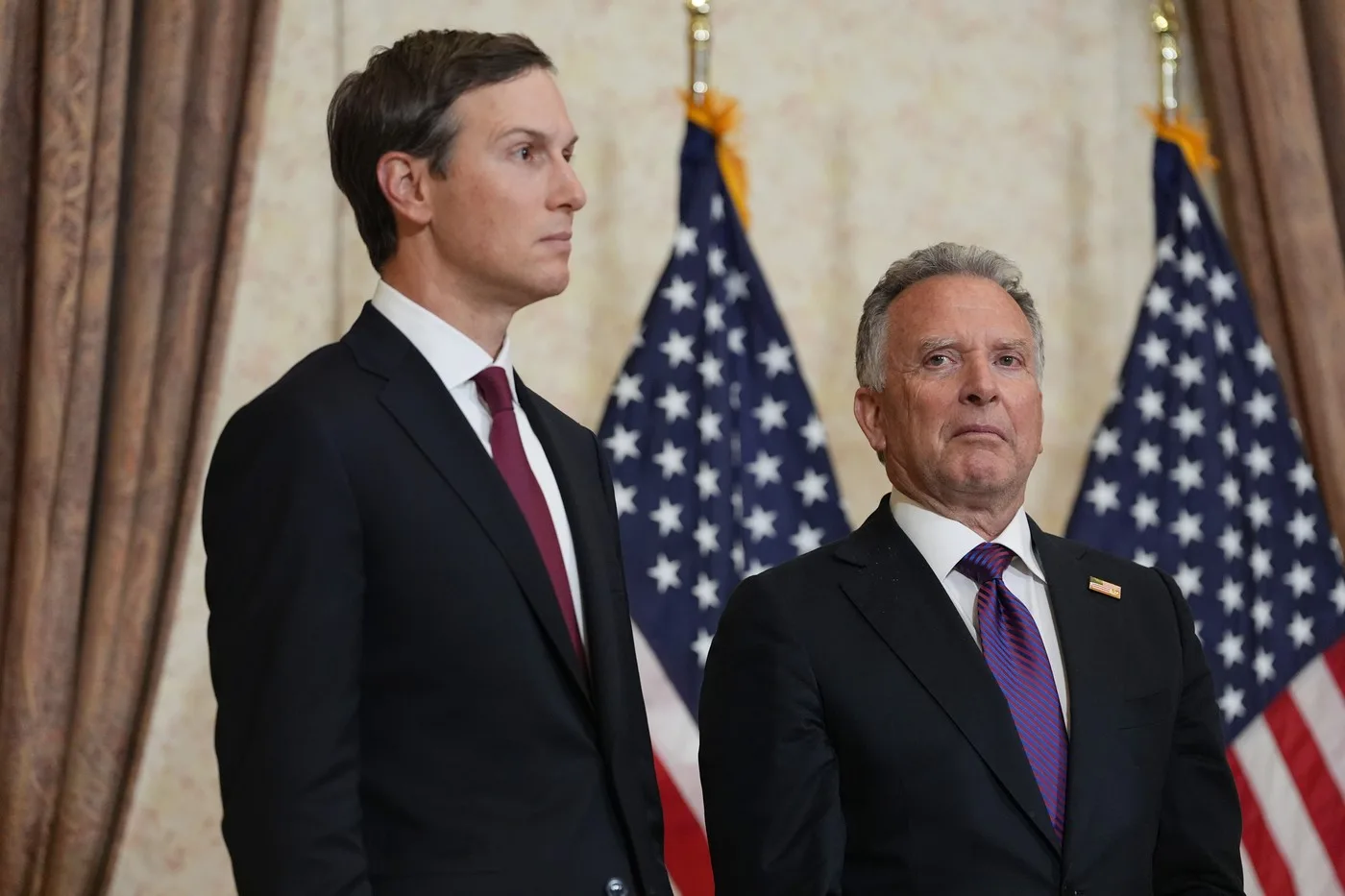 Steve Witkoff și Jared Kushner la o întâlnire oficială în fața drapelului american.