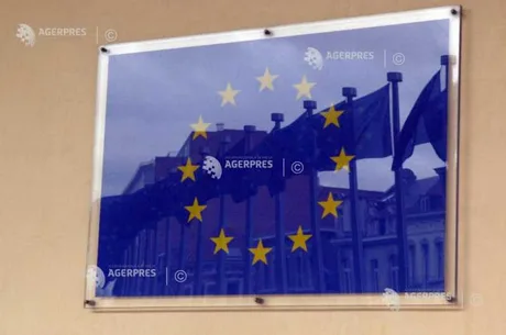 Steaguri ale Uniunii Europene reflectate pe o suprafață de sticlă.