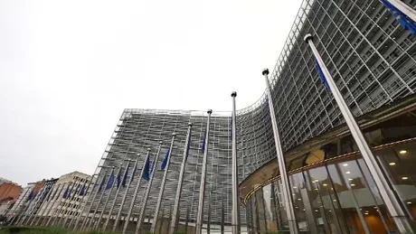 Clădire modernă cu steaguri europene în față, simbol al cooperării internaționale.