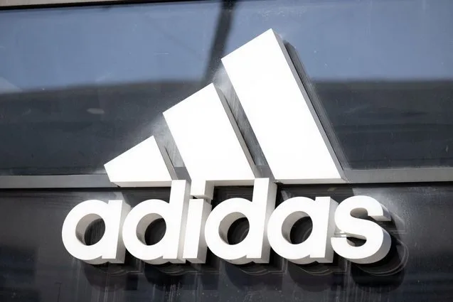 Logo-ul Adidas pe un fundal modern, simbolizând brandul sportiv iconic.