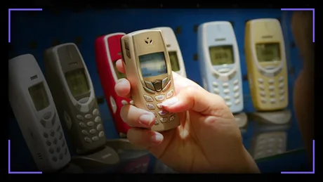 Un utilizator ține un telefon Nokia 3310, înconjurat de alte modele.