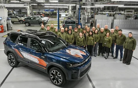 Angajați Dacia alături de un vehicul aniversar în fabrică.